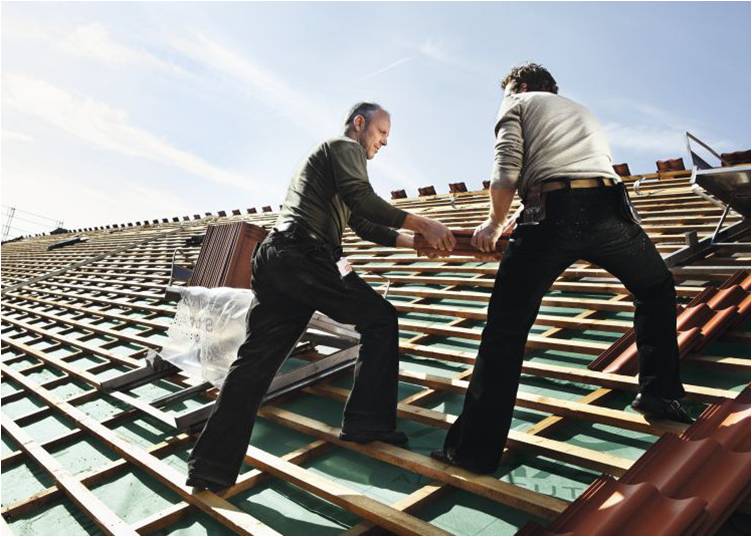 Dachdecker bei der Arbeit: Das Anreichen und Verlegen der Dachziegel wird in der Regel von jeweils einem Dachdecker übernommen. (Foto: Monier Braas GmbH)