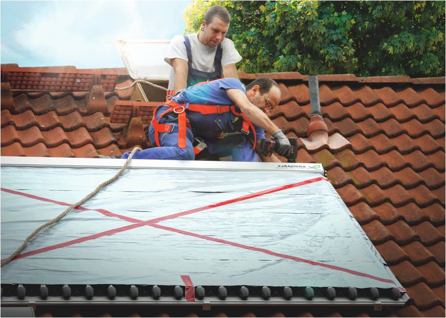 Zwei Handwerker montieren auf dem Dach einen Solarwärme-Kollektor mit einer Sicherungsleine (Foto: Paradigma)