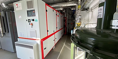 Das 3,7 Tonnen schwere Aggregat des Berliner Herstellers SES Energiesysteme ergänzt zwei Erdgasbrennwertkessel - links im Bild - bei der Wärmeerzeugung. (Foto: Nadine Auras)