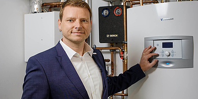 Das Bild zeigt den Bosch-Key-Account-Manager Gordon Zittlau vor dem Wärmepumpen-Gerät.