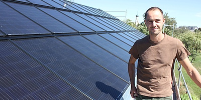 Das Bild zeigt eine Person neben der Solaranlage. 