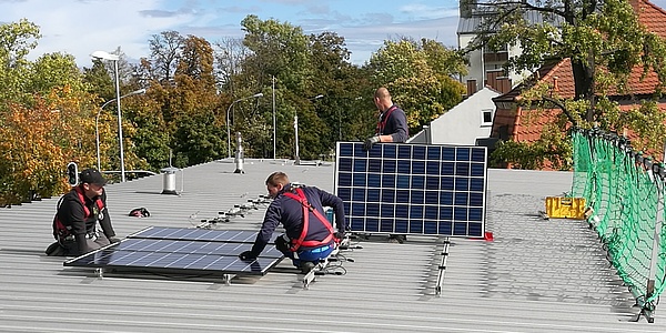 Das Bild zeigt Monteure bei dem Installieren der PV-Anlage auf dem Dach der kinderQuelle in Ingolstadt.