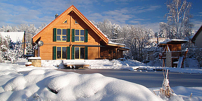 Das Bild zeigt den Energieteich und das Wohnhaus im Winter, bedeckt mit Schnee.