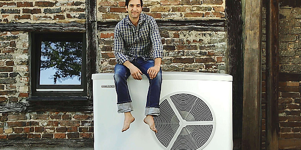 Das Bild zeigt den Schauspieler Thomas Maximilian Held sitzend auf seiner Wärmepumpe.