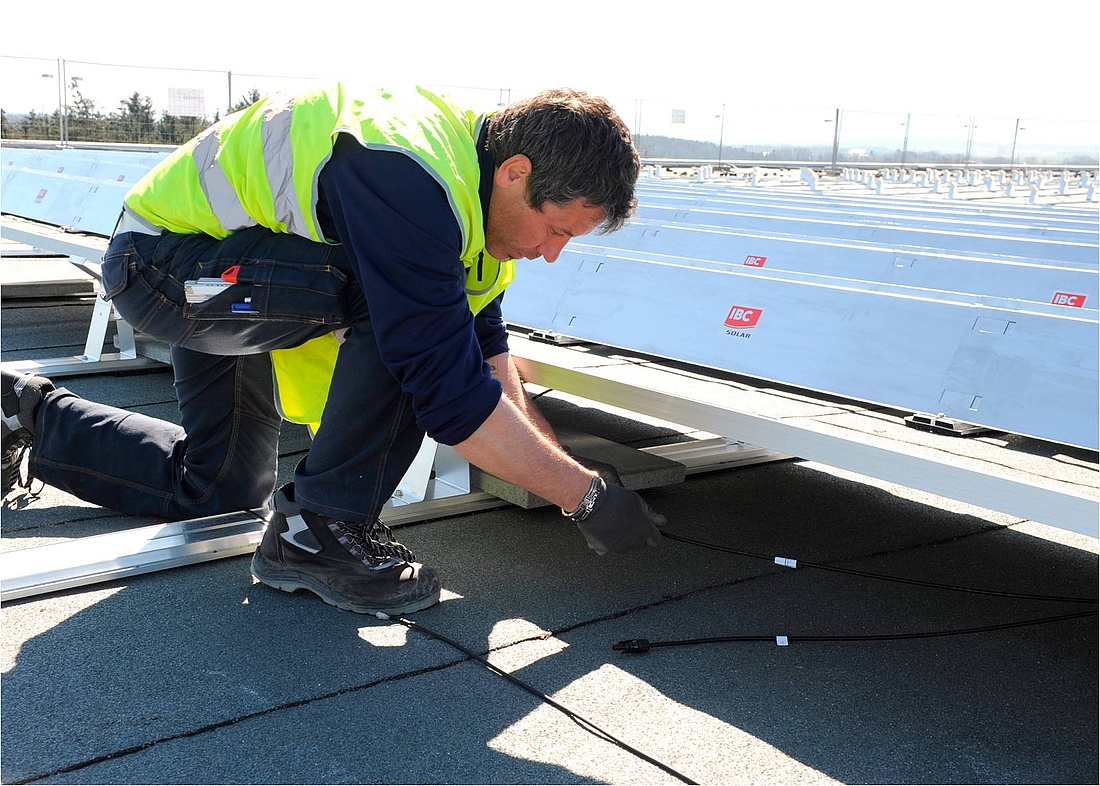 Verbindung von Solarmodulen durch MC4-Stecker auf einem Flachdach. Die Kabel werden dabei einfach mit Kabelclips an den Stützen oder Modulrahmen (hier: IBC AeroFix) befestigt. (Foto: IBC SOLAR AG)