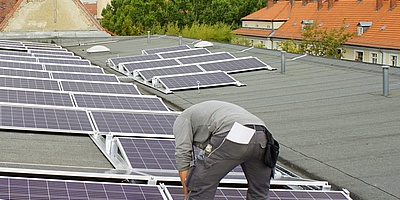 Das Bild zeigt einen Arbeiter bei dem Montieren der Solaranlage.