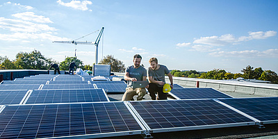 Das Bild zeigt Beteiligte bei dem Anbringen der Solaranlage auf dem Dach des Wohnhauses.