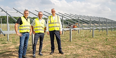 Das Foto zeigt drei Beteiligte auf dem Gelände des Solarparks.