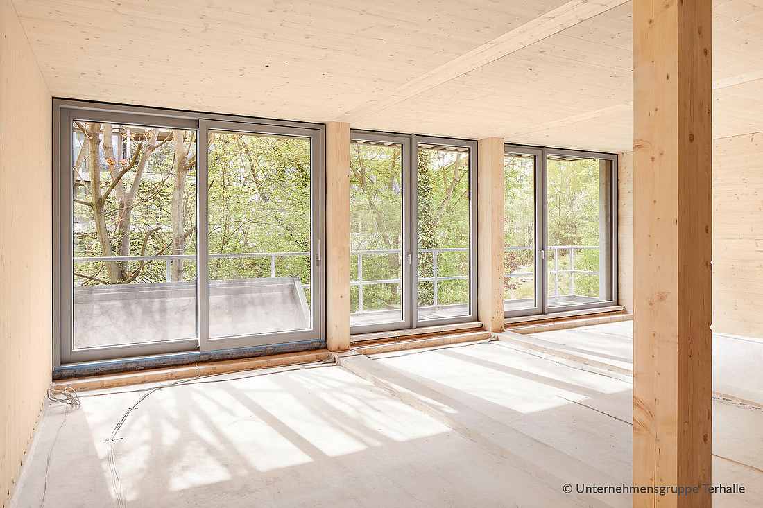 Dieses Foto zeigt ein Wohnzimmer mit einem aus Holz-Alu-Fenstertüren verkleideten Terrassenzugang