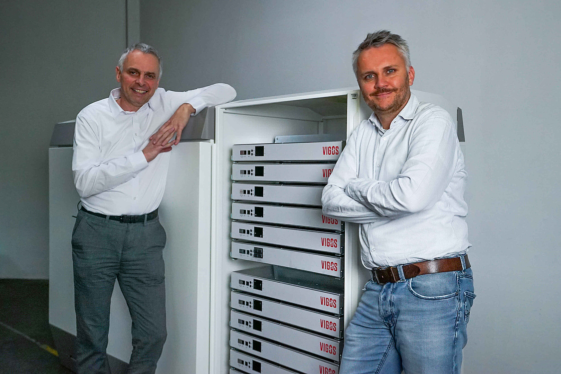 Die Geschäftsführer der BlueSky Energy GmbH Helmut Mayer und Thomas Krausse (von links nach rechts) mit ihrem neuen Vigos-LTO-Speicher. (Copyright: BlueSky Energy GmbH)